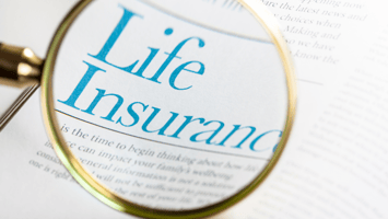 A magnifying glass focusing on the words 'Life Insurance' on a printed document, symbolizing the importance of understanding life insurance policies and options.